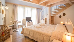 Un dormitorio con una cama grande, un escritorio con silla, una televisión y una escalera.