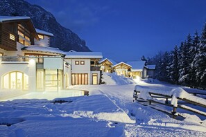 A snow-covered mountain resort with multiple buildings, including a large house with a balcony and a smaller structure with a sloped roof. - Castelir Suite Hotel (Panchia)
