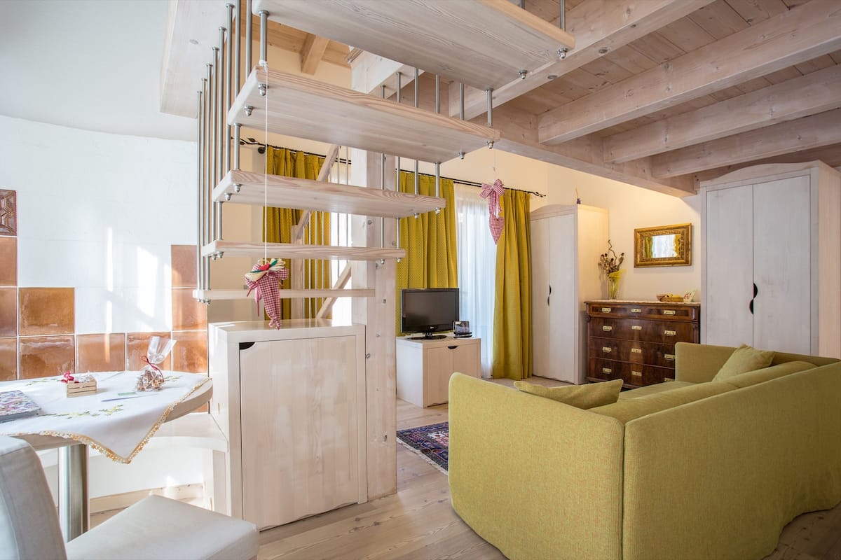 A modern living room with a sofa, a television, and a wooden staircase.