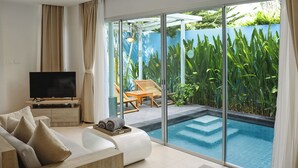 A modern living room with a TV, sofa, and a view of a swimming pool and greenery. - Villa Sonata Phuket (Chalong)