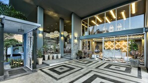 A modern hotel lobby with a geometric patterned floor, a reception desk, and a seating area with chairs and a small table. - Villa Sonata Phuket (Chalong)