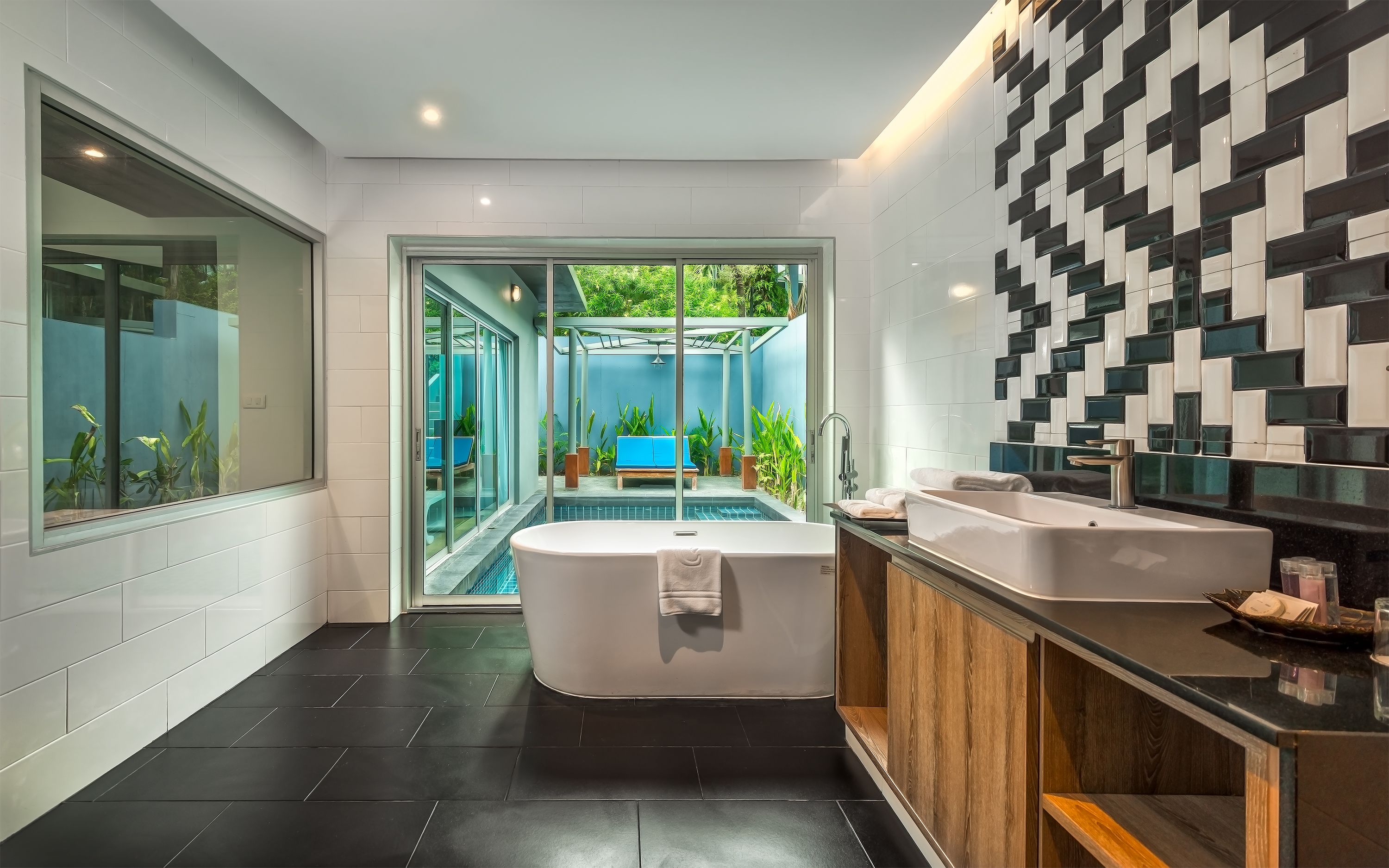 A modern bathroom with a large bathtub, a double sink, and a glass-enclosed shower area.