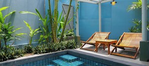 Un espace piscine doté de chaises longues en bois et d’une piscine carrelée.