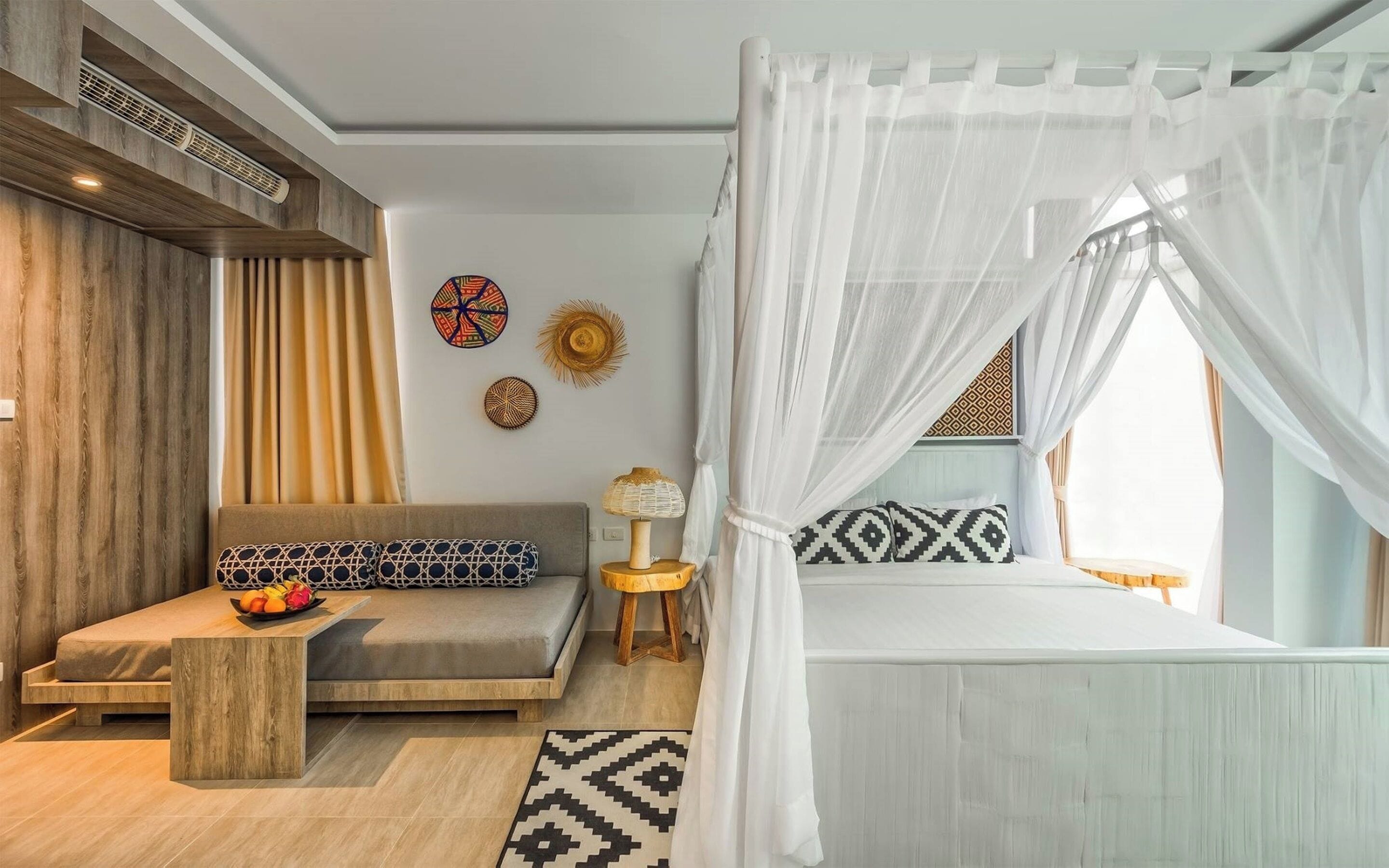 A modern bedroom with a bed, a sofa, a nightstand, and decorative wall art.