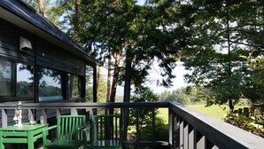 A wooden deck with a table and chairs, overlooking a forested area. - Pension Good Luck Takayama (Takayama)