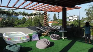 An outdoor patio with artificial grass, a small inflatable pool, bean bags, and a pergola structure. - Hotel Villa del Mar (Batumi)