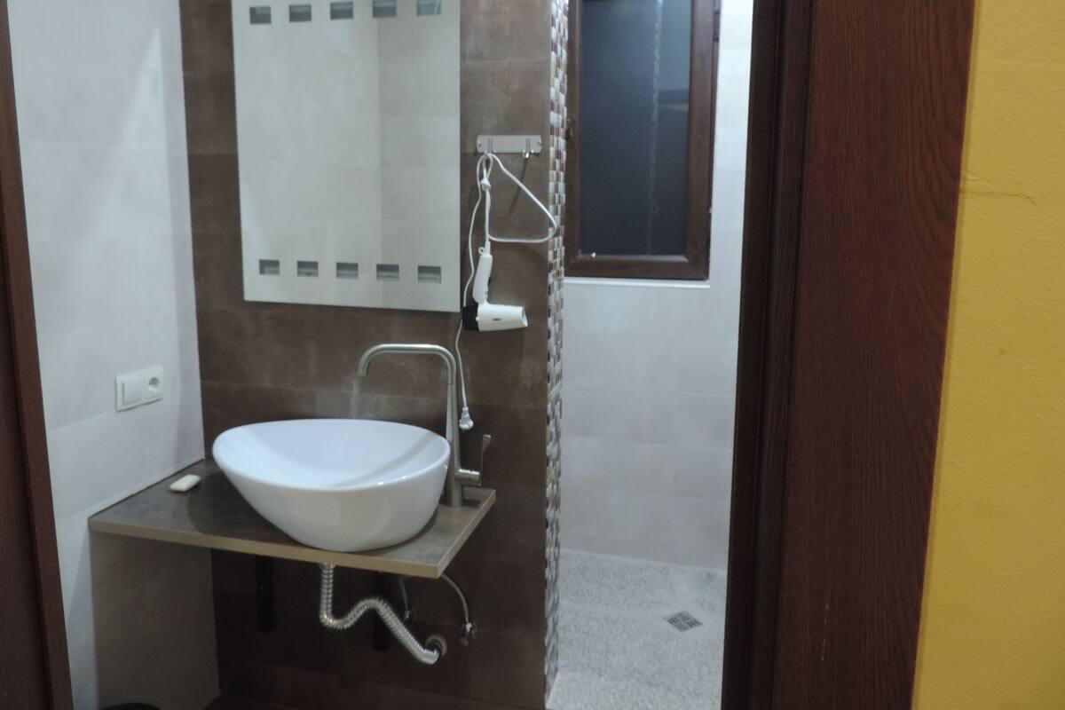 Une salle de bain avec un lavabo blanc, un miroir et un espace douche.