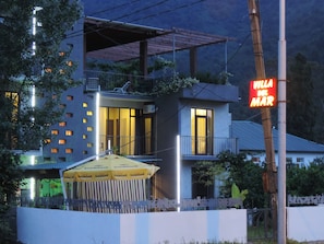 A modern building with a balcony, a sign reading "Villa del Mar", and a yellow umbrella in front.
