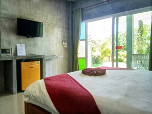 A hotel room with a bed, a television mounted on the wall, a small refrigerator, and a sliding glass door leading to an outdoor area. - Tum Mai Kaew Resort (Ko Lanta)