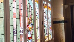 A row of stained glass windows with geometric patterns and floral designs. - Hôtel de Normandie (Amiens)