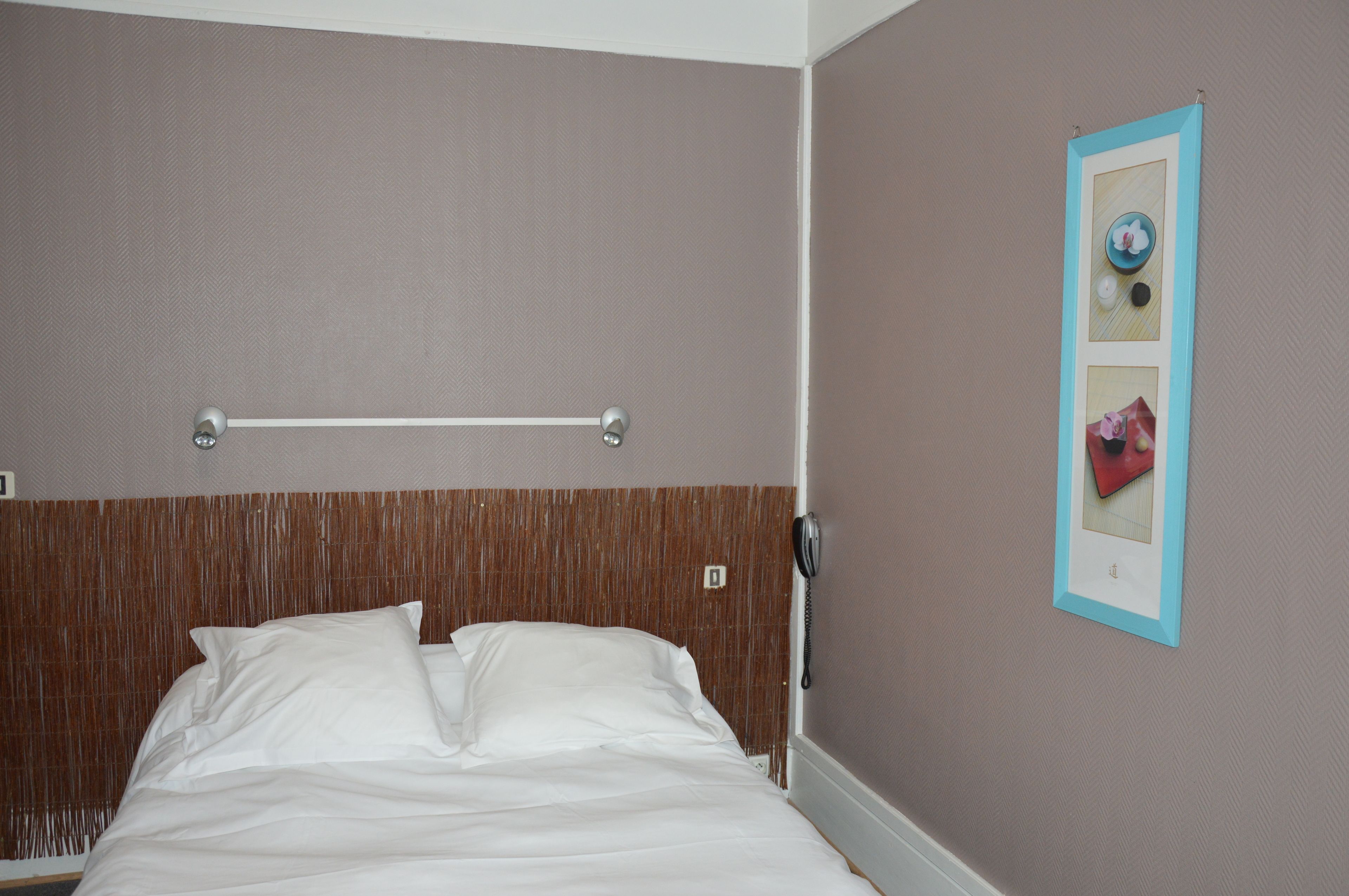 Une chambre d’hôtel avec un lit, un porte-serviettes et un tableau encadré au mur.