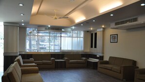 Amplia sala de estar con varios sofás y sillones dispuestos alrededor de una mesa central.
