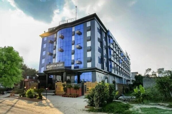 Un hôtel moderne à la façade incurvée, doté de nombreux balcons et d’une enseigne indiquant « Hôtel Shamsher Sagar ».