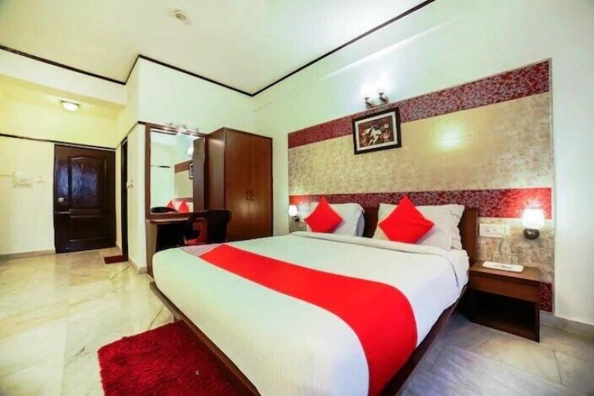 Habitación de hotel con una cama grande, un armario de madera, un escritorio con una silla y un espejo.