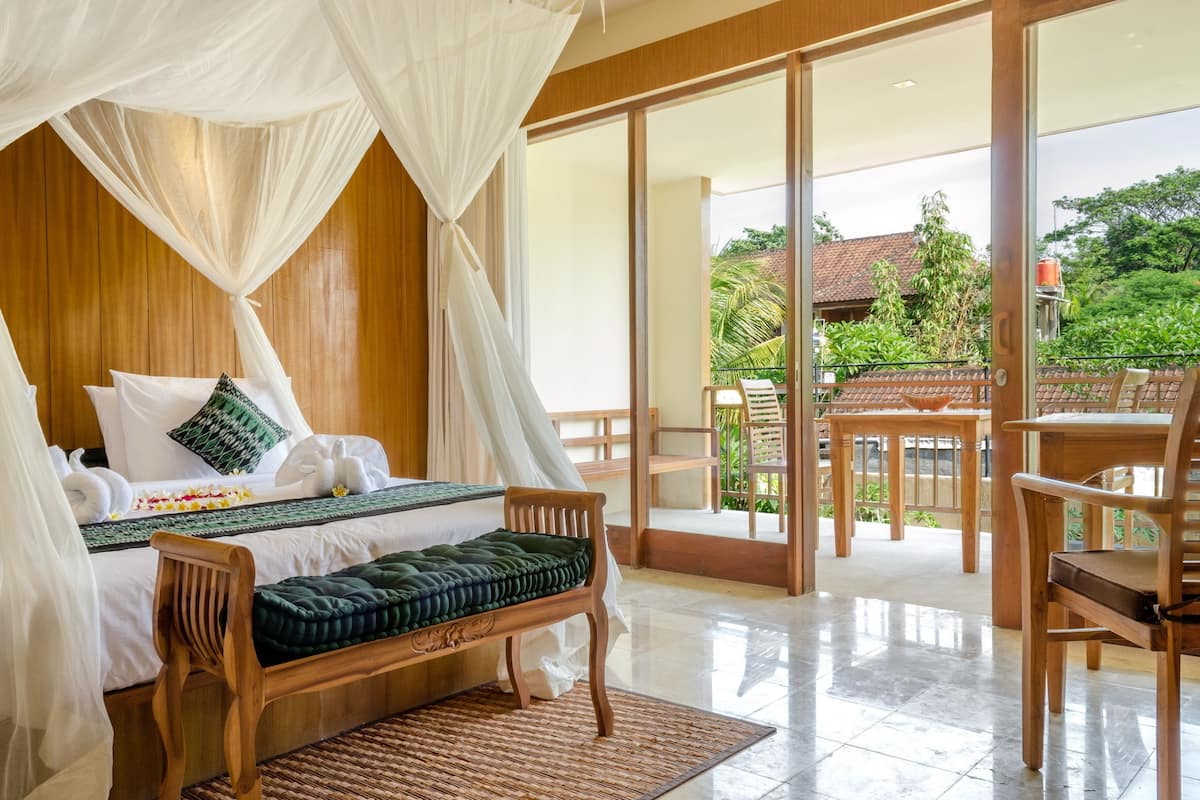A bedroom with a canopy bed, wooden furniture, and a view of the outdoors.