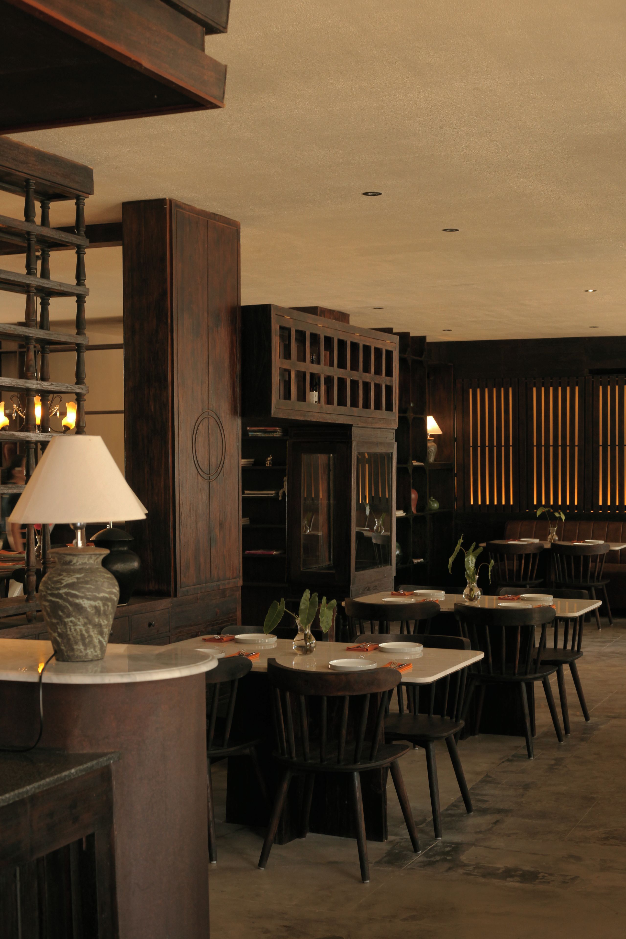 A restaurant interior with wooden furniture, a central column, and a counter with a lamp.