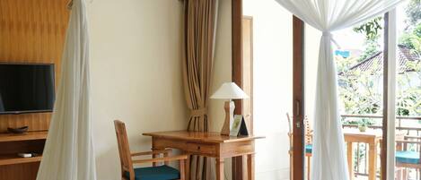 Una habitación con cama, escritorio, silla, televisión y vistas al exterior.
