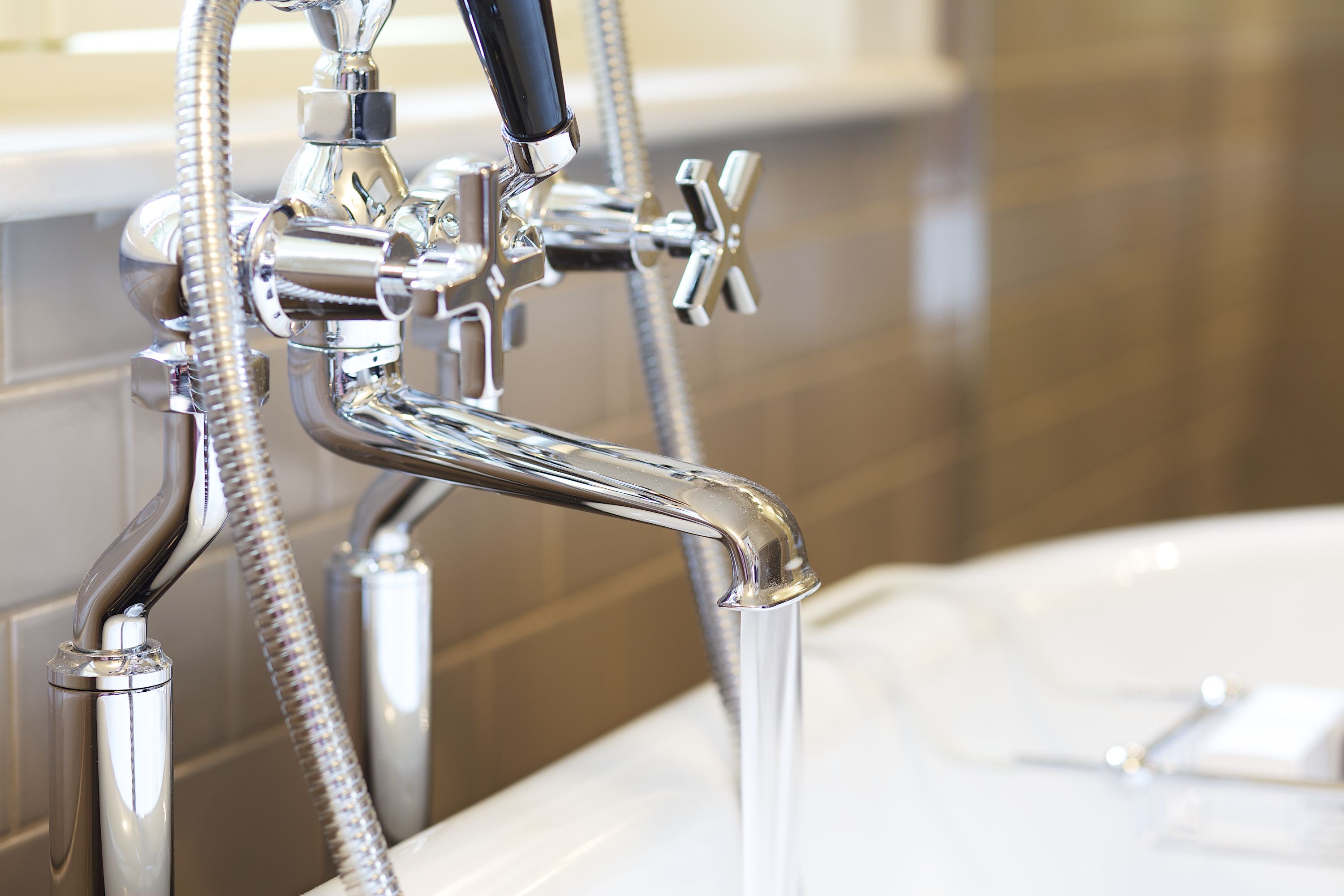 Un baño moderno con grifo y ducha de cromo, cabezal de ducha y bañera.