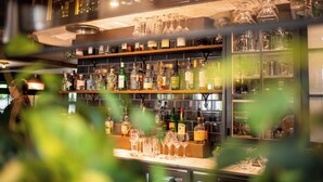 A bar area with shelves stocked with bottles and glasses, and a counter with more bottles and glasses. - Hurley House Hotel (Maidenhead)