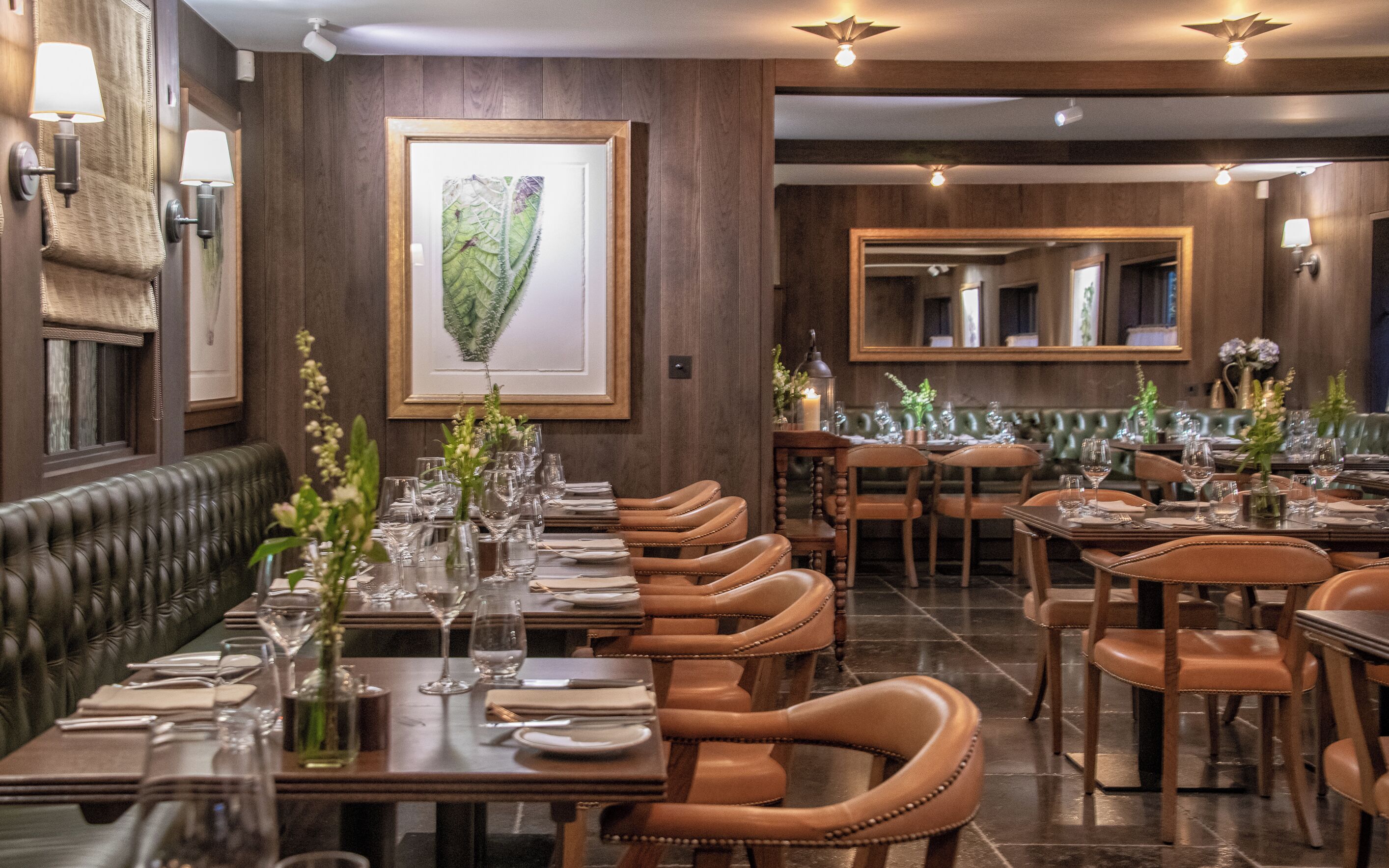 Interior de restaurante con asientos de cuero, mesas de madera y obras de arte enmarcadas en las paredes.