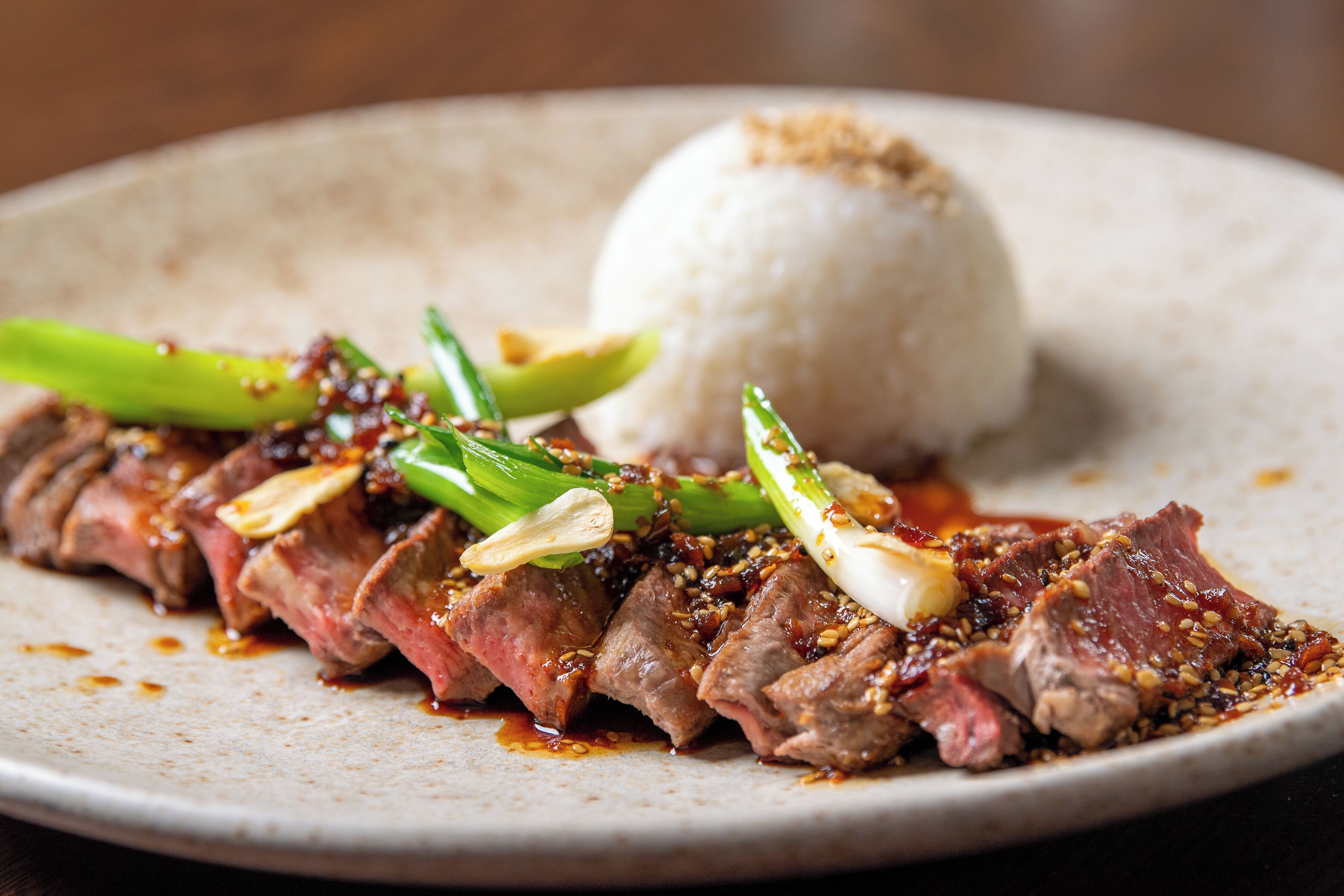 A plate of sliced meat with vegetables and rice.