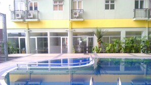 Ein Pool mit geschwungener Kante, umgeben von einer gefliesten Terrasse.