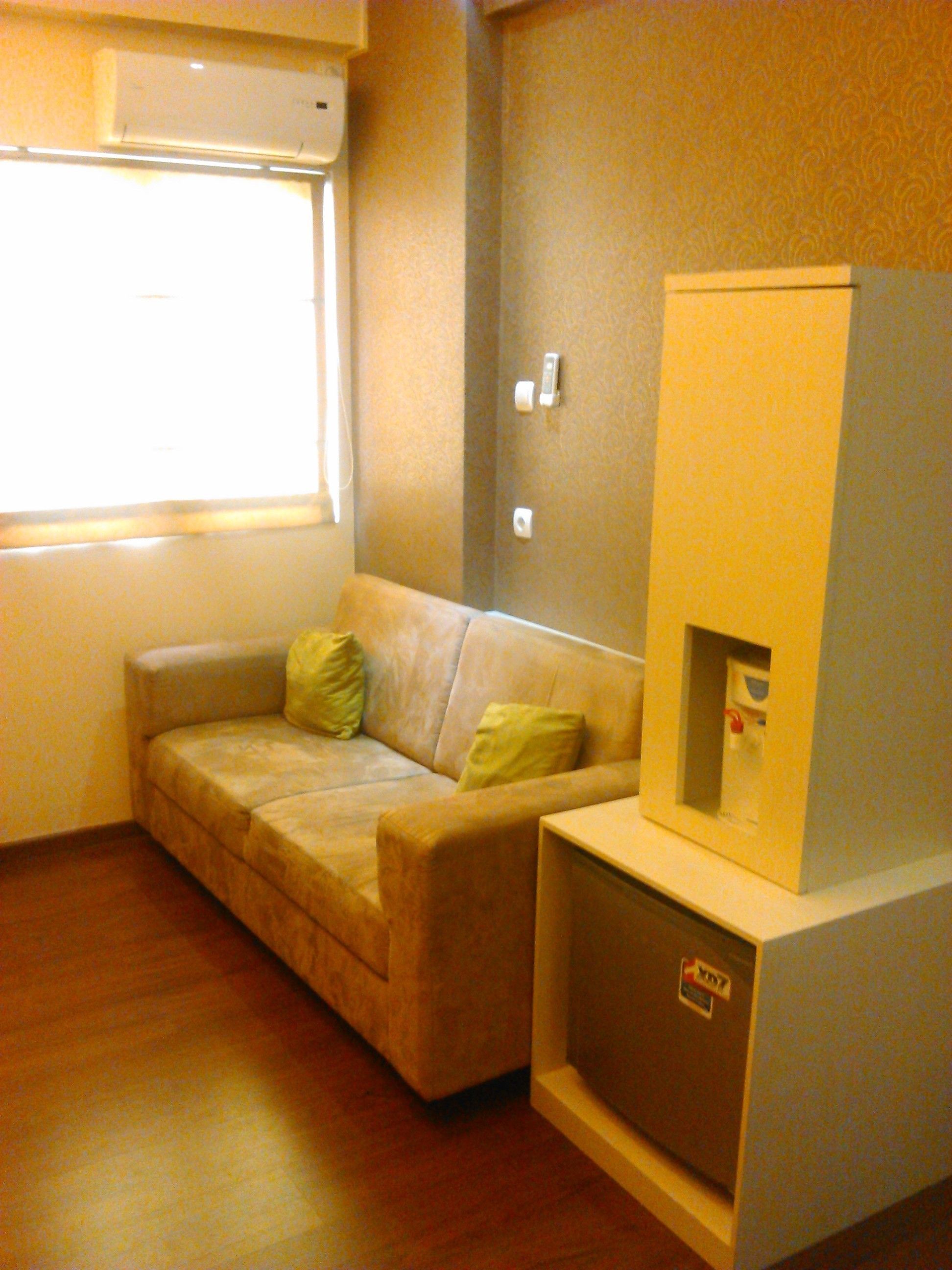 A small, cozy room with a sofa, a small cabinet, and a window.