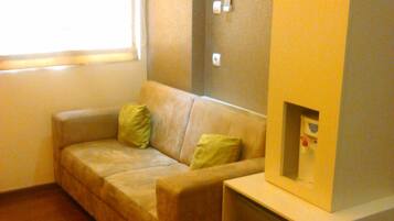 A small, cozy room with a sofa, a small cabinet, and a window.