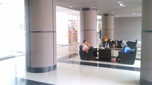 Eine geräumige Lobby mit großen Säulen, einer Sitzecke und einem Geschäft im Hintergrund.