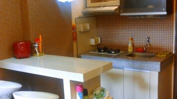 A compact kitchen with a microwave, stove, and a small bar area with stools.