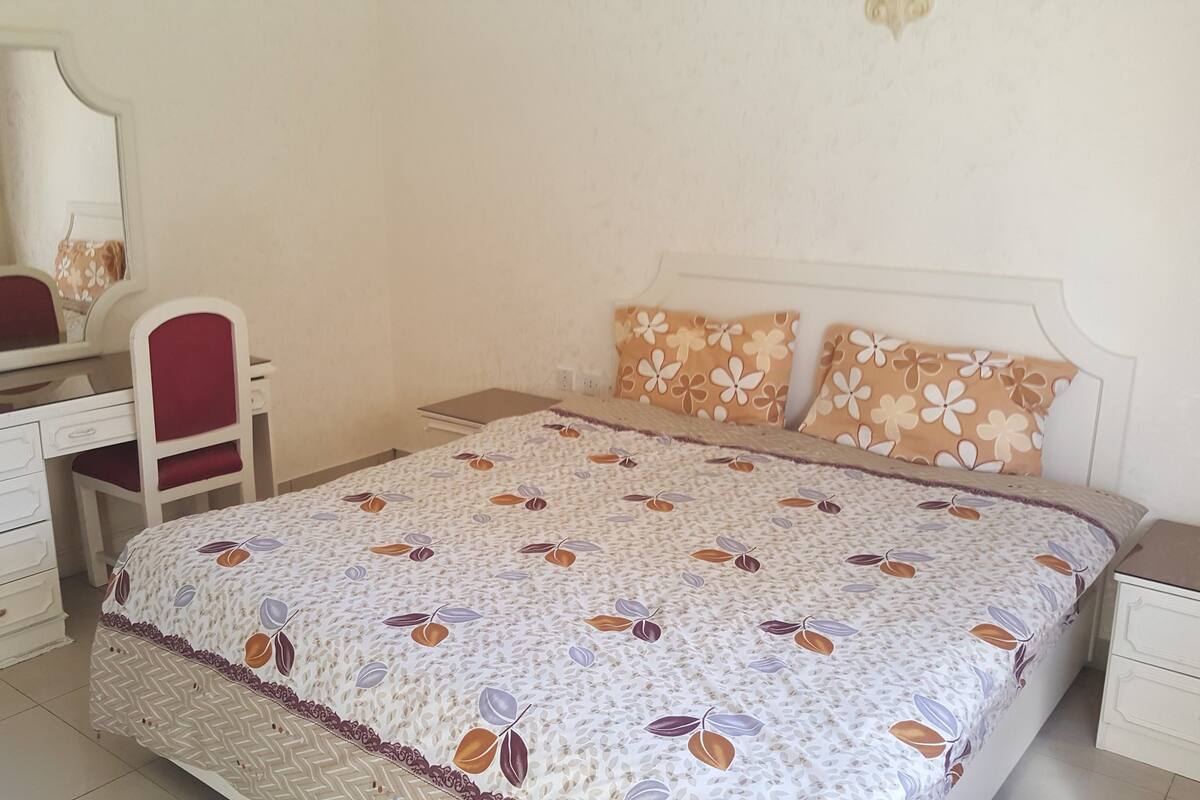 Una camera da letto con un letto, una scrivania, una sedia e uno specchio.