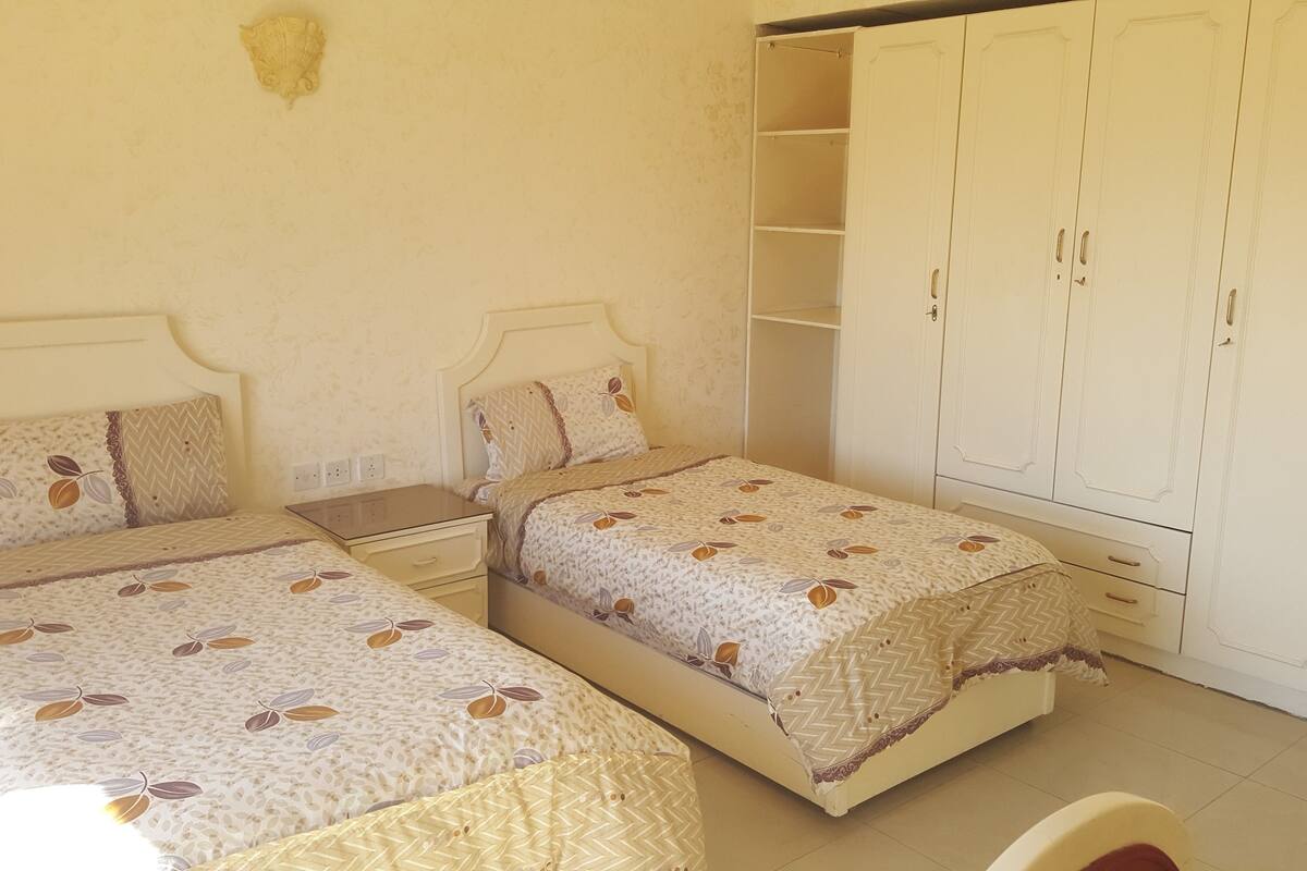 Una camera da letto con due letti, un armadio e un comodino.