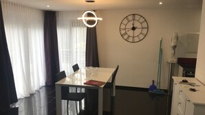 Un comedor moderno con una mesa blanca, sillas negras y un reloj de pared.