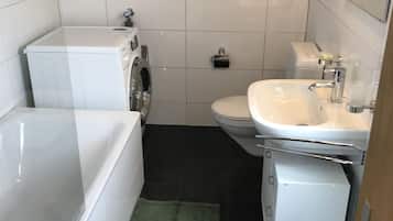 A compact bathroom with a white toilet, sink, and a washing machine.