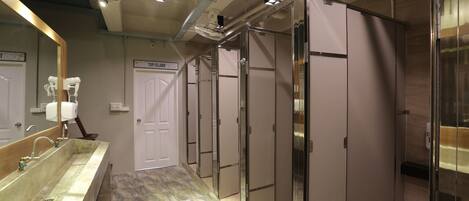 Un baño moderno con un lavamanos grande, un espejo, un dispensador de toallas y un ventilador.