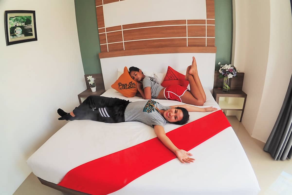 A bed with a red and white striped bedspread, a wooden headboard, and two pillows with text.