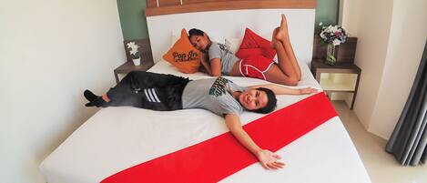 A bed with a red and white striped bedspread, a wooden headboard, and two pillows with text.
