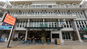 A hostel with a signboard, outdoor seating, and a storefront. - Pop-In Hostel Aonang (Krabi)