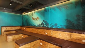 A Pop In Hostel with wooden benches and a tropical-themed wall. - Pop-In Hostel Aonang (Krabi)