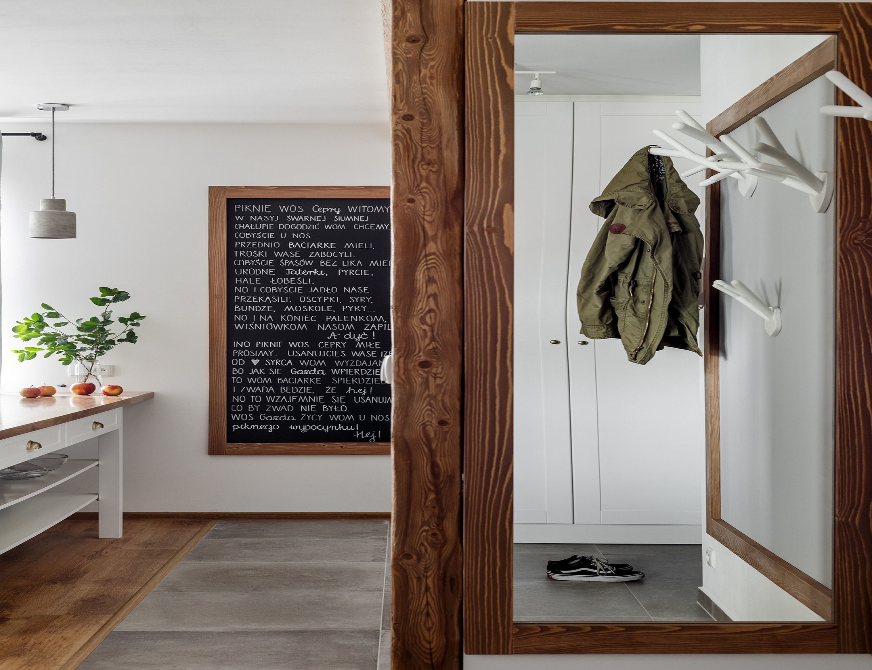 A room with a wooden floor, a white door, and a coat rack with a jacket hanging on it.