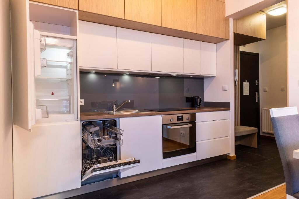 Een compacte keuken met inbouwapparatuur, een vaatwasser en een kleine oven.