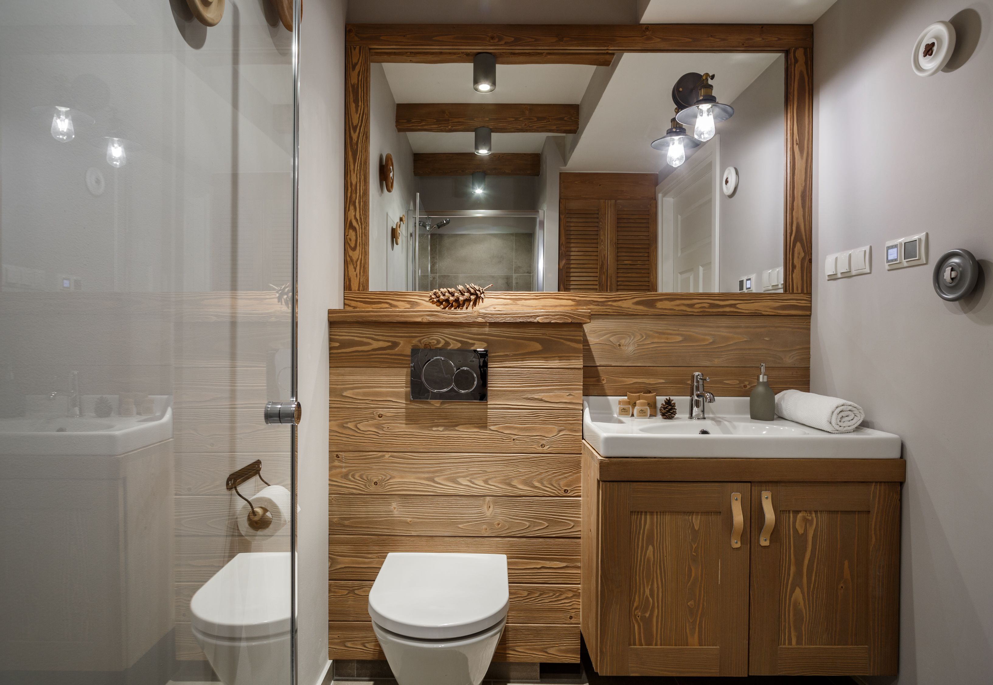 Un baño moderno con tocador de madera, un espejo y una ducha.