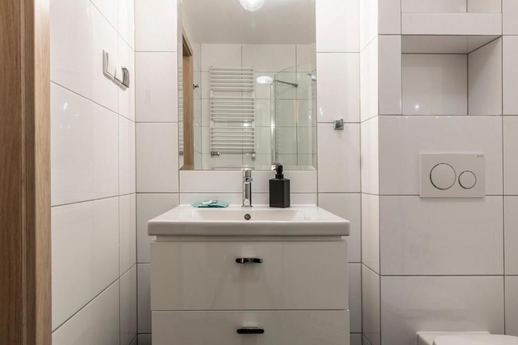 Un bagno moderno con lavandino bianco, specchio e cabina doccia in vetro.