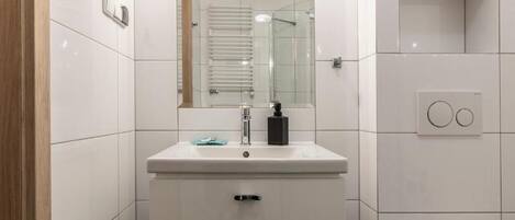 A modern bathroom with a white sink, mirror, and glass shower enclosure.