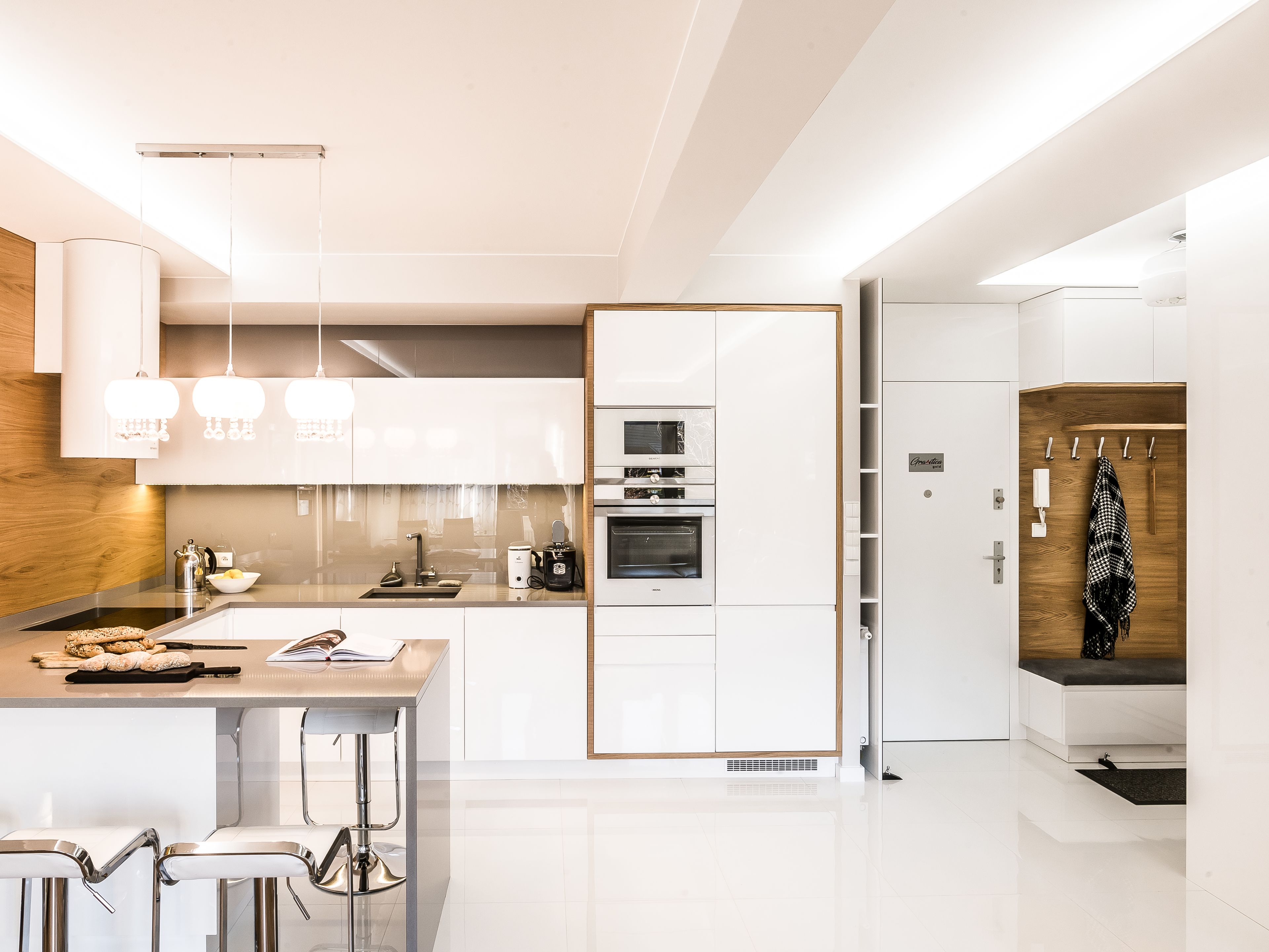 Una cocina moderna con armarios blancos, electrodomésticos de acero inoxidable y una barra con taburetes.