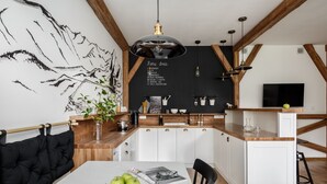 A modern kitchen with white cabinets, a wooden countertop, and a blackboard menu. - Tatrytop Apartamenty Granitica (Zakopane)