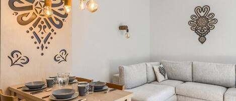 A dining area with a wooden table set for four, a grey sofa, and wall decor.