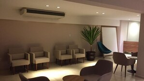 A modern waiting area with several chairs and a small table, a potted plant, and a blue chair.