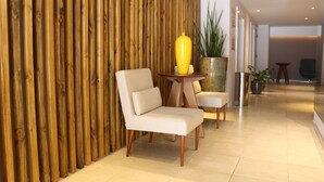 A modern interior with a wooden panel wall, a yellow vase on a table, and a potted plant.