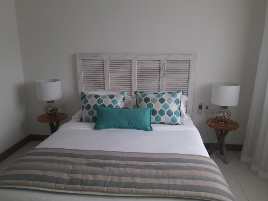 A hotel room with a bed, two bedside tables, and a headboard with shutters.